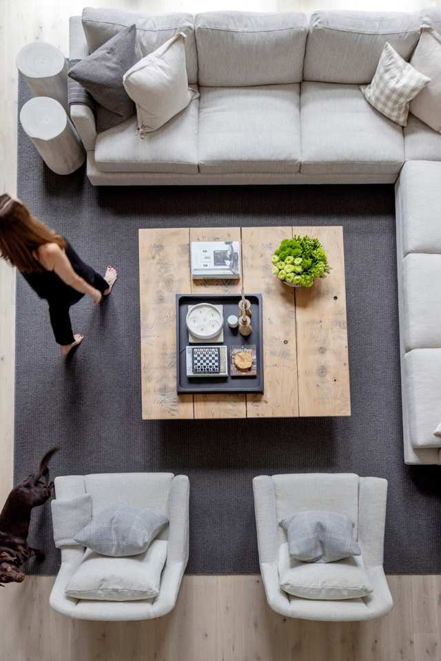 woman and dog walking through cozy living room with beige sectional and wooden coffee table